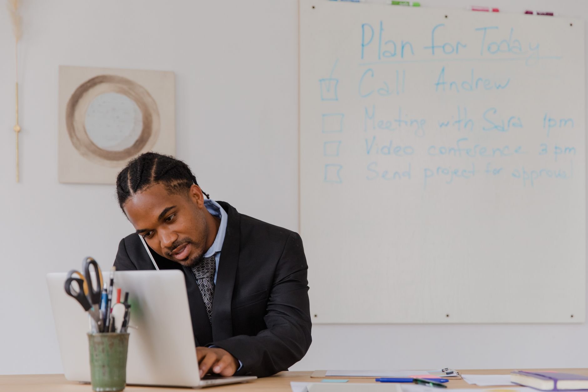 Businessman at his desk in an office working on a laptop and making phone calls.